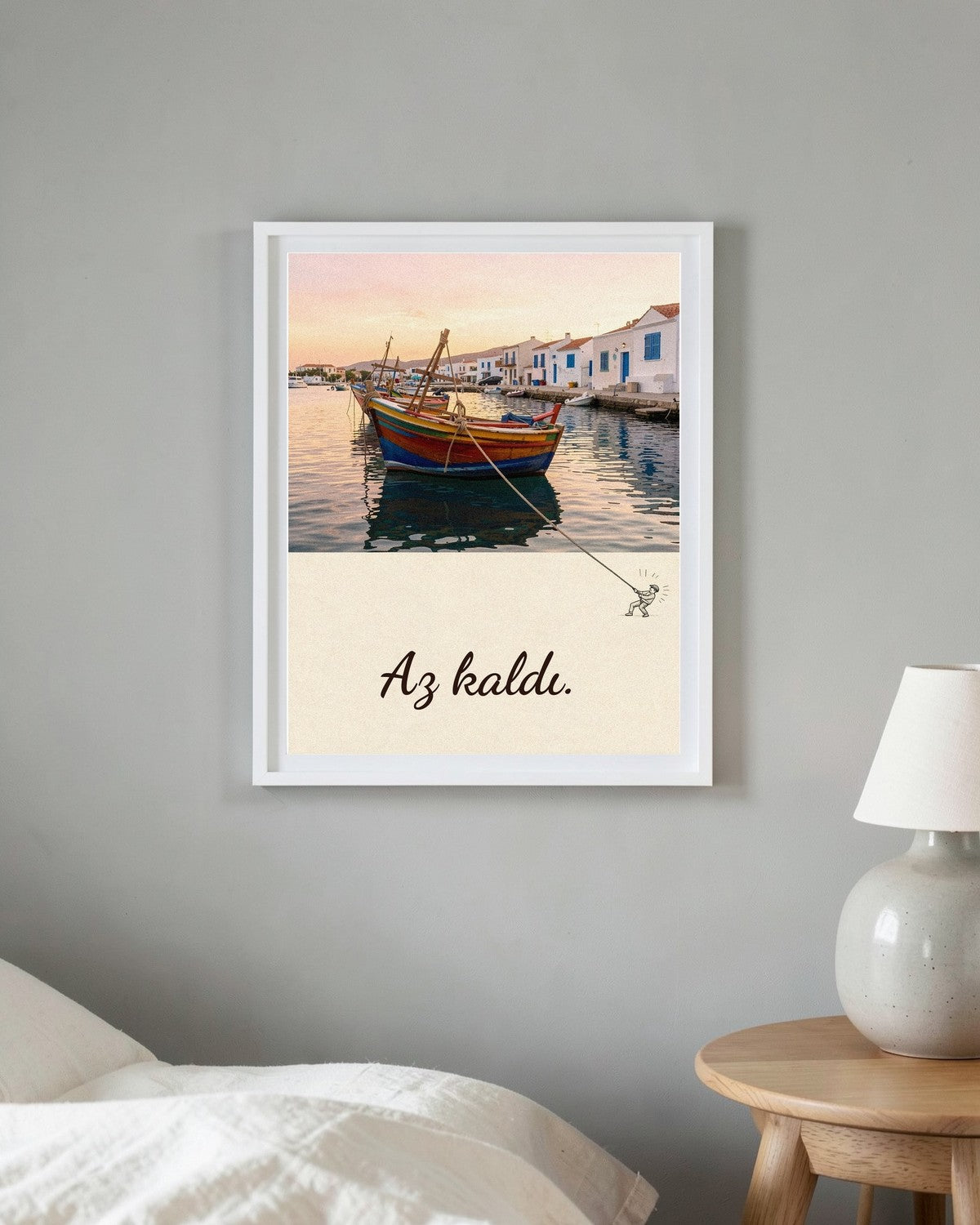 Beyaz çerçeveli Az kaldı posteri, yatak odasında yatağın ve lambalı komodinin yanındaki gri duvarda