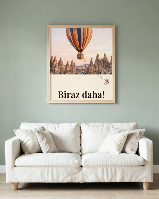 Ahşap çerçeveli Biraz daha! posteri, yeşil duvarda beyaz kanepenin üzerinde asılı.