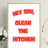 Ahşap çerçeveli, beyaz zeminde kırmızı-pembe harflerle Hey Siri, Clean the Kitchen yazan poster, yanında beyaz güller.